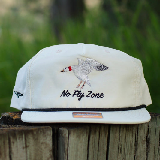 no fly zone snow goose rope hat on a log with a blurred background 