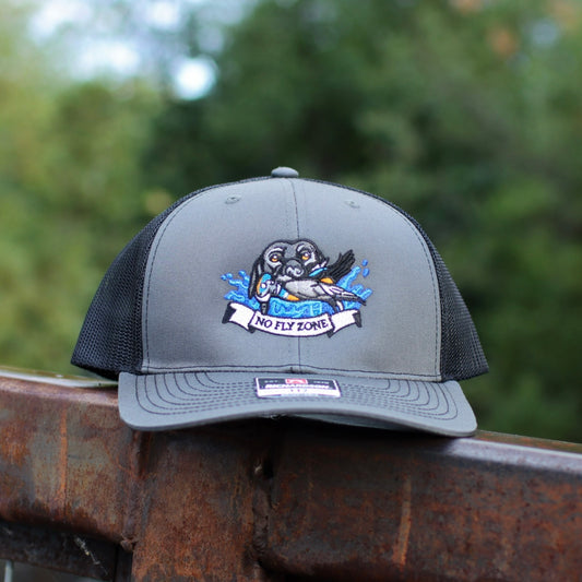 no fly zone waterfowl hat with a embroidered dog and harlequin on post with blurred background 